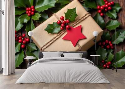 Christmas gift with holly decoration and red star ornament on rustic wood surface Wall mural