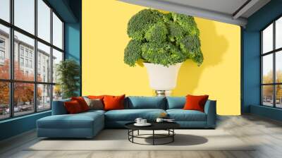 Light bulb with green broccoli flowers on a strong yellow background. Renewable electricity production minimal concept. Wall mural