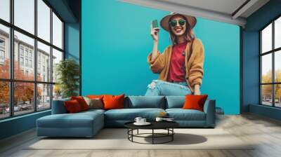 Young indian traveler lady sitting on baggage and showing card Wall mural