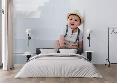 Beautiful baby sitting on white stairs in Santorini, Greece, wearing a hat and a vintage outfit Wall mural