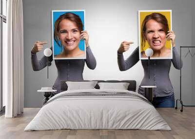 Girl holding a picture of her face happy and angry Wall mural