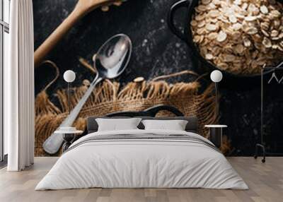 Top view of two black bowls and spoon with raw oatmeal on a black background. Breakfast with fibers for a balanced diet. Oat photo Wall mural