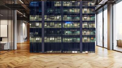 Office building exterior during late evening with interior lights on and people working inside night timelapse Wall mural