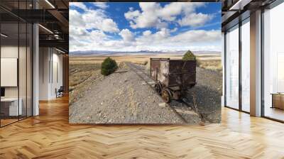 Old mining ore cart on tracks underneath a beautiful blue sky with clouds in the Nevada desert at the Berlin Ghost Town. Wall mural