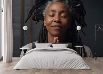 smiling elderly black woman with braids and closed eyes in deep prayer Wall mural