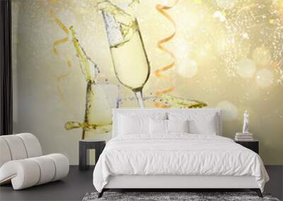 Two festive champagne glasses with streaming paper on golden bokeh background with lights Wall mural