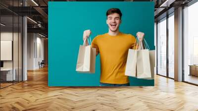 On a blue background, an excited man holds shopping bags in a t-shirt Wall mural