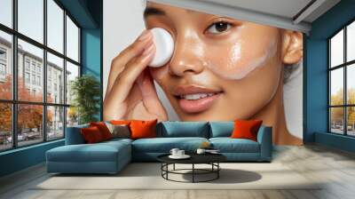 The woman is removing her makeup with a cotton pad and toner in a close-up shot Wall mural