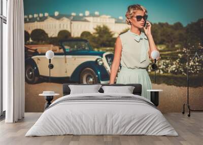 Beautiful lady with mobile phone near classic convertible Wall mural