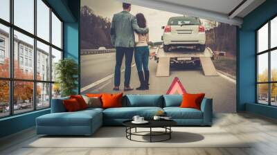 Couple near tow-truck picking up broken car Wall mural