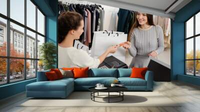 Happy woman customer paying with credit card in fashion showroom Wall mural