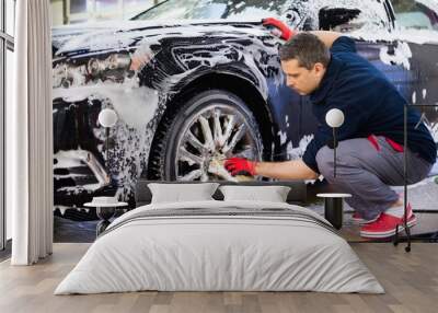 man worker washing car's alloy wheels on a car wash Wall mural