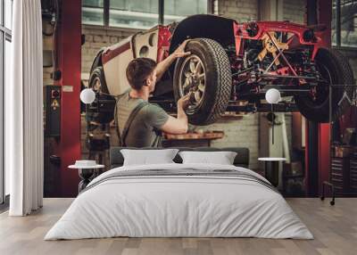 Mechanic working on classic car wheels and suspension in restoration workshop Wall mural