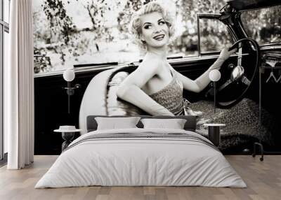 Smiling retro woman in convertible Wall mural