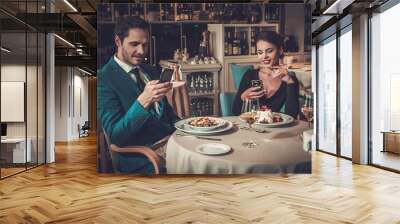 Stylish couple with mobile phones in a restaurant Wall mural