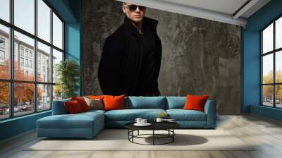 Stylish young man in black coat and sunglasses Wall mural