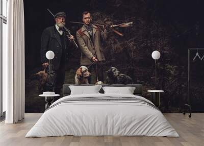 Two hunters with dogs and shotguns in a traditional shooting clothing. Wall mural