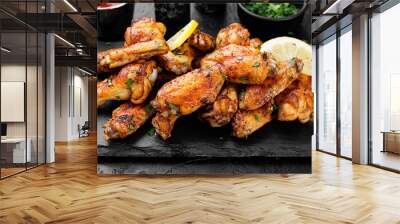 Baked chicken wings served with different sauces and lemon. Black background Wall mural