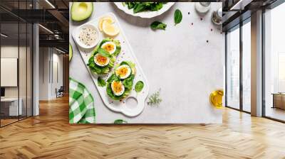 Healthy toast with sliced avocado, boiled eggs, spices and fresh spinach. Delicious breakfast or snack on gray stone background. top view, space for text	 Wall mural