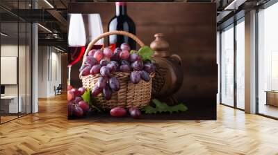 Ripe grapes in wicker basket on wooden background. Wall mural