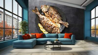 Tasty grilled fish dorado with  lemon on kitchen table. Wall mural