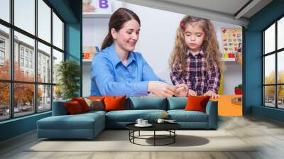 Toddler girl in child occupational therapy session doing sensory playful exercises with her therapist. Wall mural