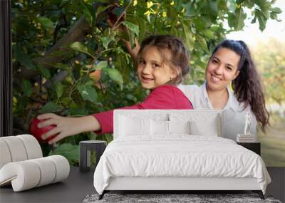 Two sisters picking apples in an orchard Wall mural