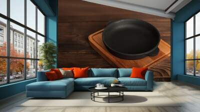 Empty cast iron round frying pan on textured wooden background close-up and copy space. Wall mural