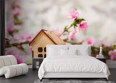 Small wooden cabin close-up and copy space. Miniature house, flowering branch in the spring. The concept of rush, purchase, exchange, home return and time. Wall mural