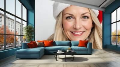 In a Santa hat, a middle-aged Caucasian woman with long blonde hair is smiling at the camera Wall mural