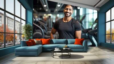 Smiling young Indian man wearing sportswear posing in gym Wall mural