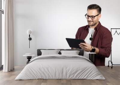 Casual dressed business man using tablet computer, acting worried and looking on tablet. Studio portrait, picture on white background Wall mural