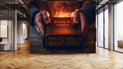 Closeup of a man holding the glowing Holy Bible book on the wooden table. Male Christian person studying and reading God's word for salvation and forgiveness of sins. Religious belief, Jesus gospel Wall mural