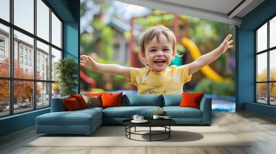 Closeup of the beautiful and cute little toddler boy, jumping or bouncing on the blue child trampoline outdoors in his backyard on a sunny summer day, smiling at the camera, leisure fun home activity Wall mural