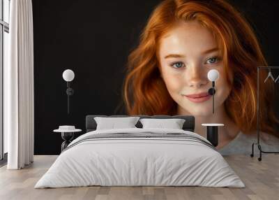 Closeup studio photography of a beautiful young woman with red hair wearing an olive green t shirt, looking at the camera, and smiling. Isolated on a black background, pretty girl model with freckles Wall mural