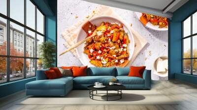 Potato wedges on a plate on a table with some roasted pepper and crumbled feta cheese  top view with hard light and golden fork served for two persons - quick lunch idea Wall mural