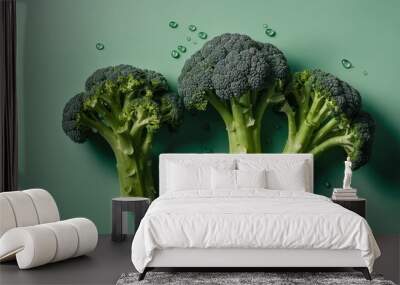 Three large heads of broccoli are displayed on a green table Wall mural