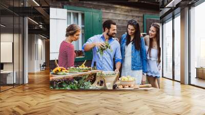 Man pouring olive oil into salad with girls at barbecue outdoors Wall mural