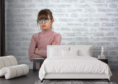 Angry school girl over white brick wall background, sign and gesture concept. Little girl with sassy expression. angry little girl on white background. Wall mural