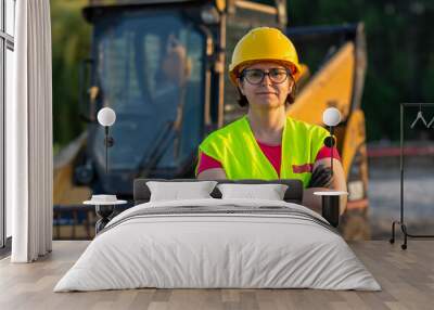 cheerful female excavator operator on construction site. Woman construction apprentice learning to drive heavy equipment Wall mural