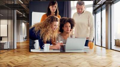 Young people working in modern office, discussing in front of laptop Wall mural