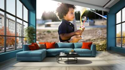 African american baby blowing soap bubbles in the park. Wall mural