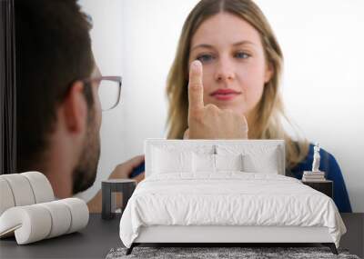 Attractive male doctor ophtalmologist checking the eye vision of beautiful young woman in modern clinic. Wall mural