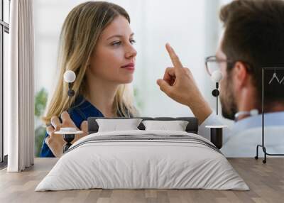 Attractive male doctor ophtalmologist checking the eye vision of beautiful young woman in modern clinic. Wall mural