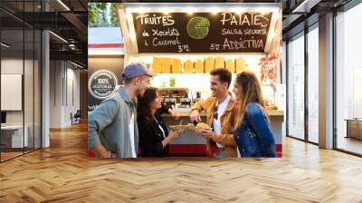 Attractive young group of friends visiting and buying fast food in eat market in the street. Wall mural