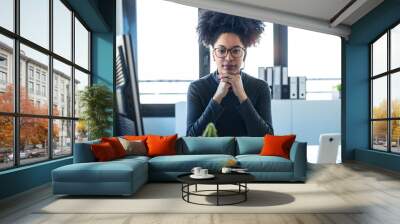 Beautiful afro business woman relaxing while looking at camera in the office. Wall mural