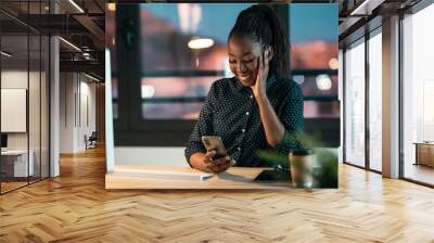 Beautiful business woman sending messages with mobile phone while working in the office. Wall mural