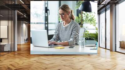 Beautiful mature business woman working while typing with a laptop on a desk in the office at home. Wall mural