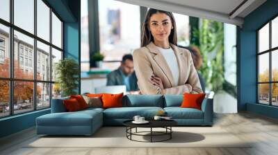 Beautiful young business woman standing while smiling looking at camera in the office Wall mural