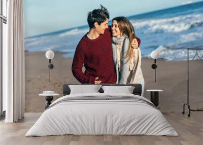 Beautiful young couple in love enjoying the day in a cold winter on the beach. Wall mural